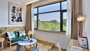 Ein modernes Zimmer mit großem Fenster, einem grünen Sofa, einem kleinen Tisch und einer Lampe.
