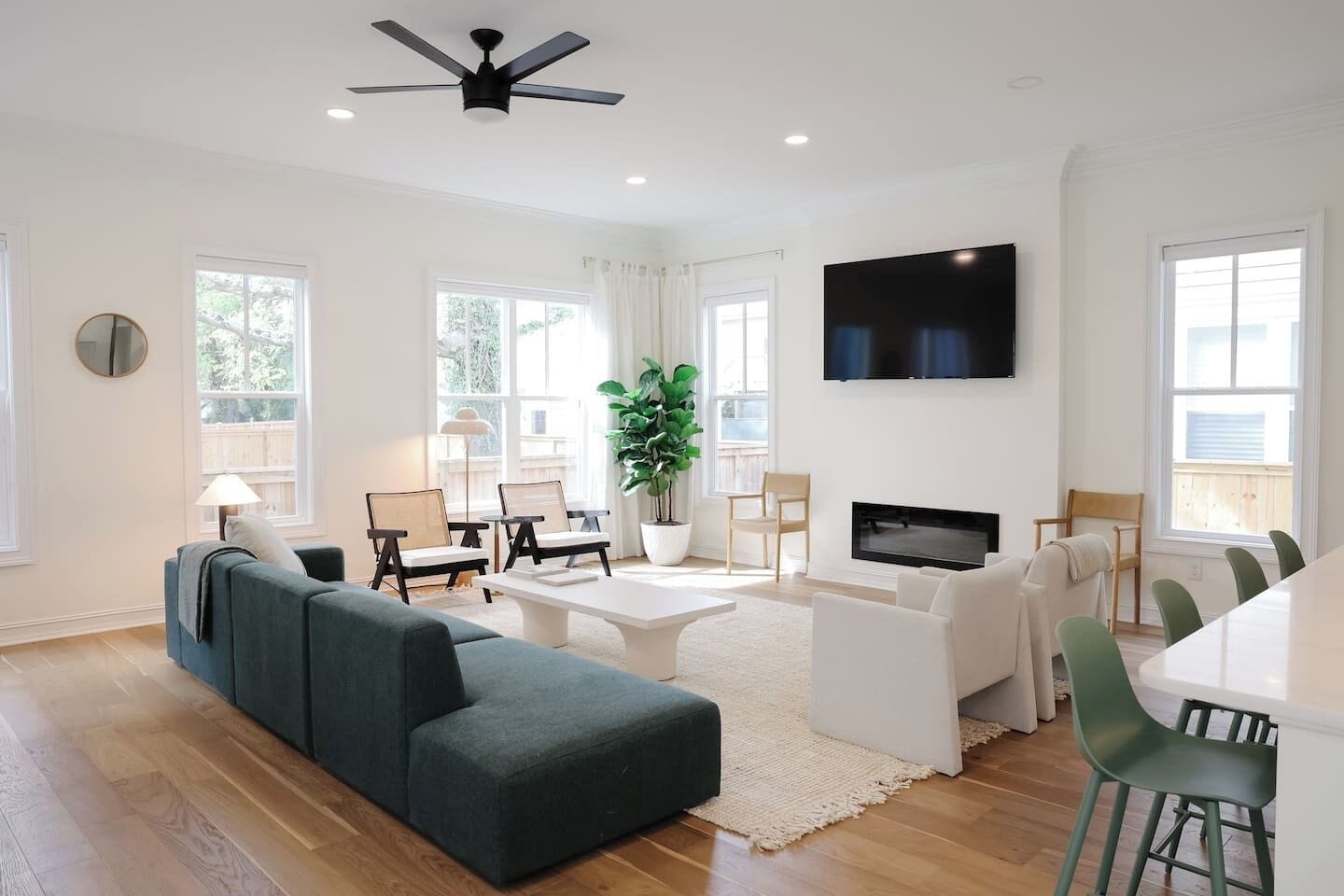 A modern living room with a sectional sofa, a coffee table, a TV, and a dining area with chairs.