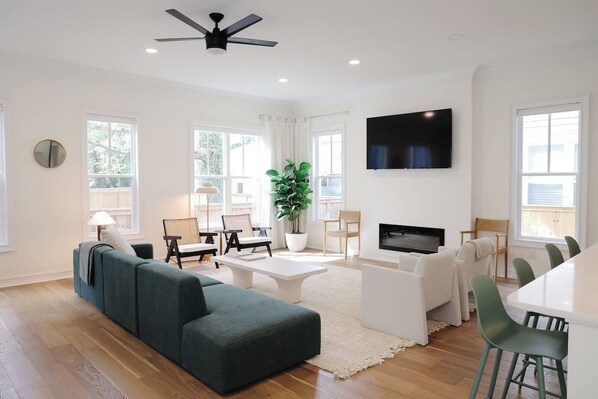 A modern living room with a sectional sofa, a coffee table, a TV, and a dining area with chairs. - Modern home with lookout in the heart of downtown (Wilmington)