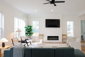 A modern living room with a flat-screen TV, a fireplace, and a large window. - Modern home with lookout in the heart of downtown (Wilmington)