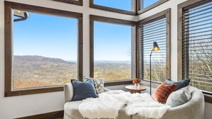 Un rincón acogedor con vistas a un paisaje montañoso a través de amplias ventanas.
