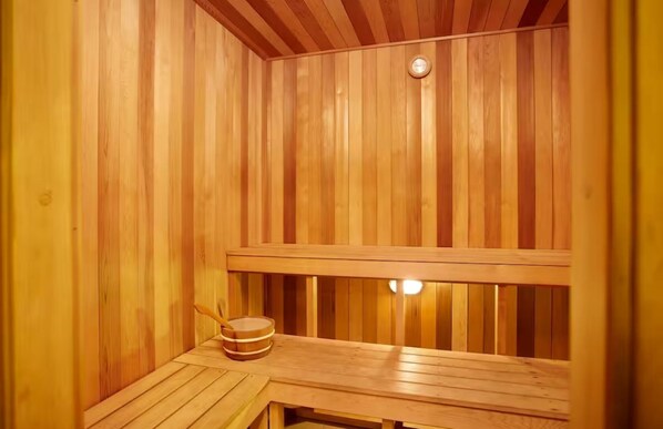 A wooden sauna with a bench and a small table with a bowl and a spoon. -  Coastal Luxe Apartment with Ocean & River Views (Surfers Paradise)