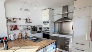 A modern kitchen with a wooden countertop, stainless steel appliances, and white cabinetry. - Blauer Elefant by Interhome (Kitzbühel)
