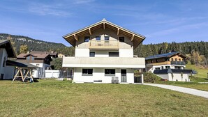 A modern two-story house with a balcony, surrounded by a grassy yard and other houses. - Leitner by Interhome (Filzmoos)