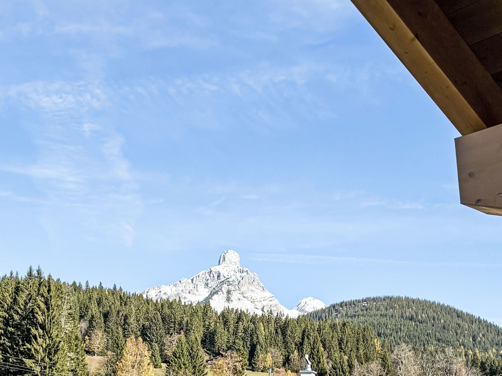 Ein Berggipfel mit bewaldeter Vordergrund und blauem Himmel.