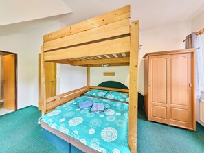 A bunk bed with a wooden frame and a patterned bedspread, a wardrobe, and a door leading to another room. - Penzion Natty by Interhome (Cerny Dul/Cista)