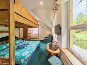 A bunk bed room with a TV, a small table, and a view of greenery outside. - Penzion Natty by Interhome (Cerny Dul/Cista)