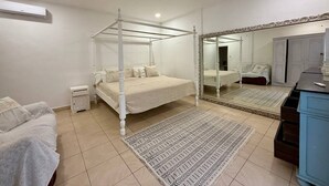 A bedroom with a four-poster bed, a large mirror, a dresser, and a small bedside table. - Villa White Orchid - Enclosed living area - Seminyak center - Quiet Private Pool (Seminyak)