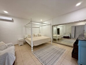 A bedroom with a four-poster bed, a large mirror, a dresser, and a small bedside table. - Villa White Orchid - Enclosed living area - Seminyak center - Quiet Private Pool (Seminyak)