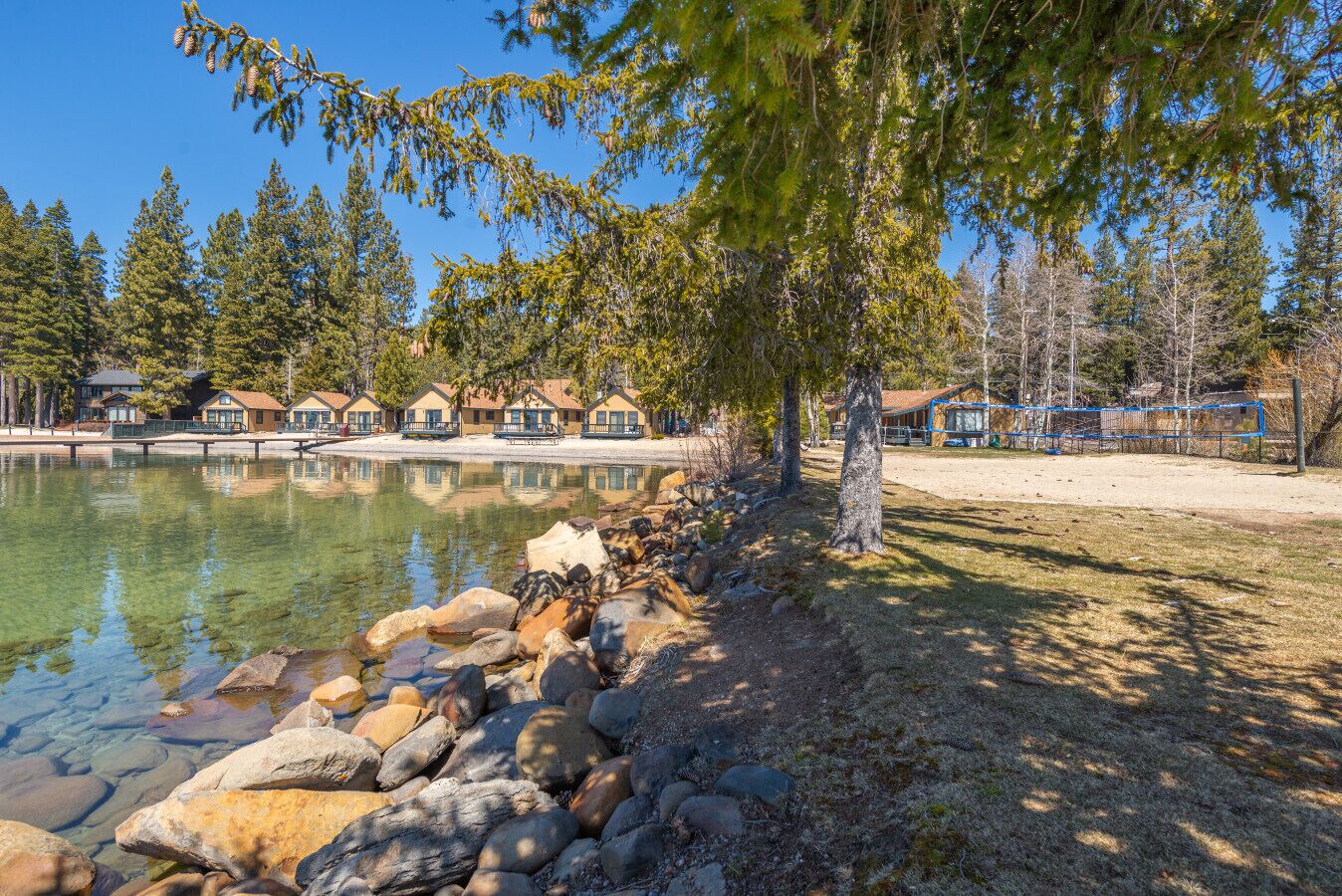 A lakeside property with a row of cabins, a clear lake, and a rocky shoreline.