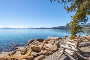 A lakeside view with a wooden bench and rocks in the foreground. - Lakeside Condo 300 feet to Beach Near Northstar (Tahoe Vista)
