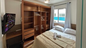 A hotel room with a large wooden wardrobe, a bed with white linens, a ceiling fan, and a window with curtains. - Apartment in the heart of São Paulo (São Paulo)