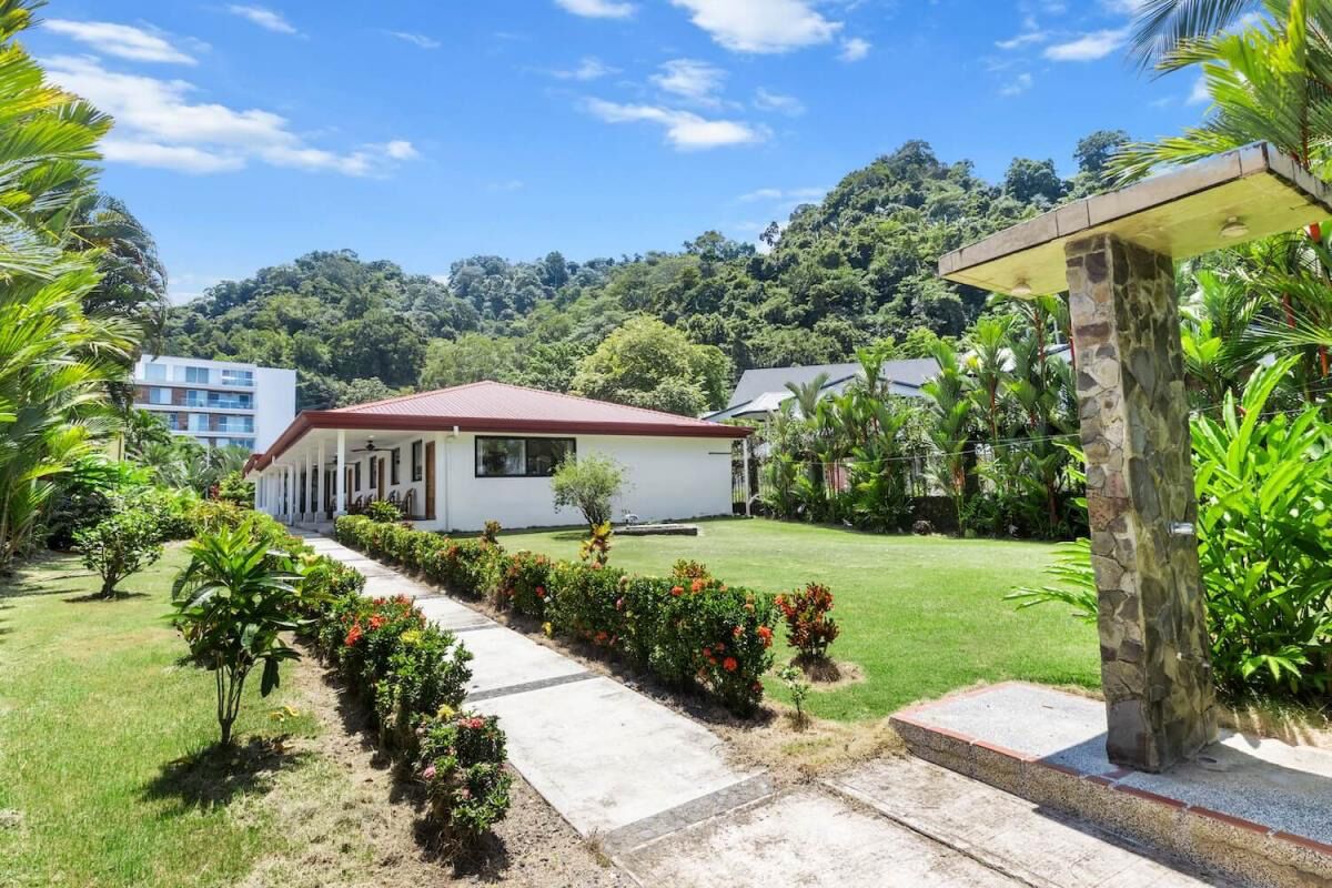 A modern house with a red roof, surrounded by a well-maintained garden and a pathway leading to the entrance.
