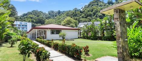 A modern house with a red roof, surrounded by a well-maintained garden and a pathway leading to the entrance.