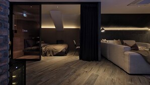 Moderni hotellihuone, jossa on sänky, sohva, työpöytä ja suuri ikkuna.