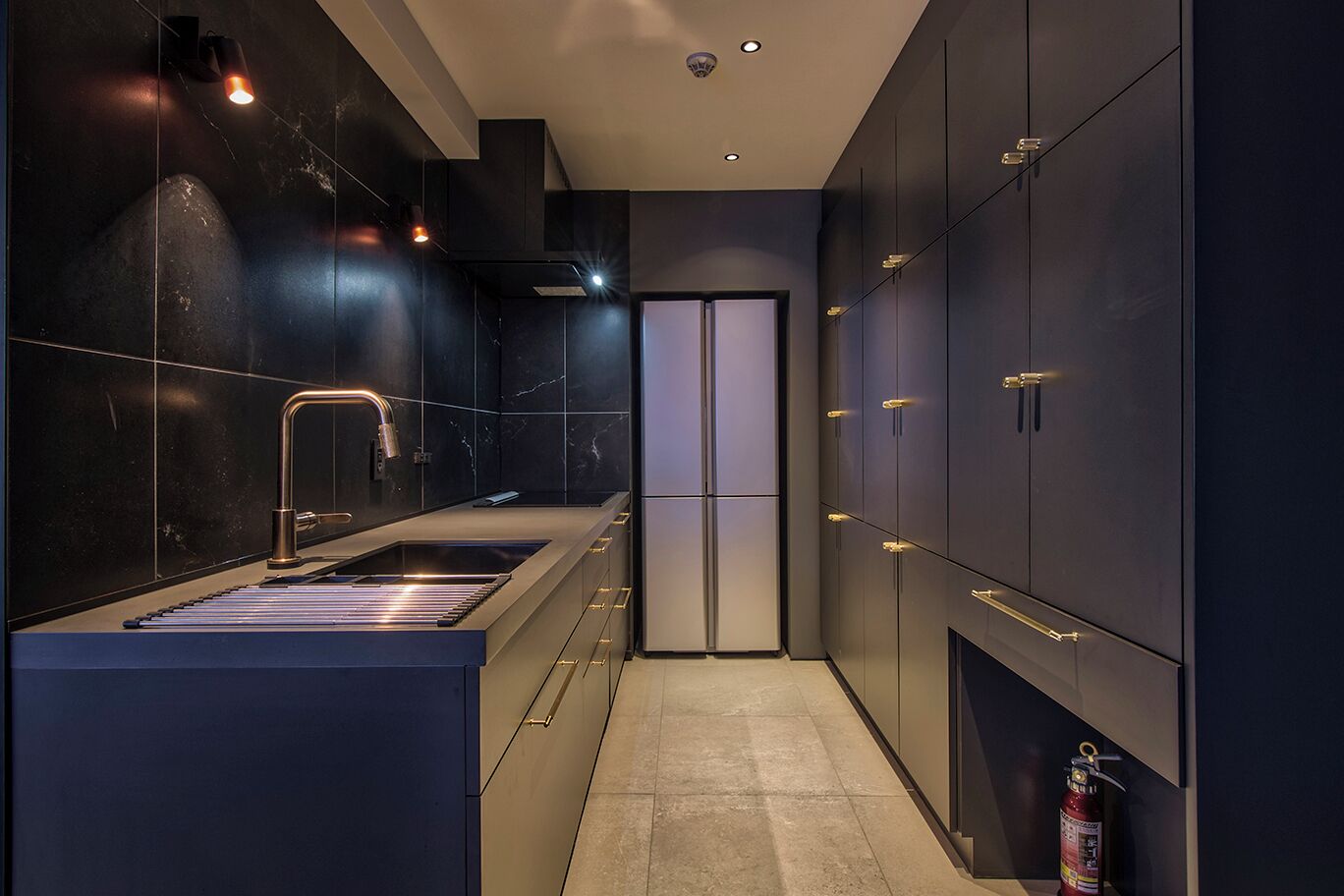 A modern kitchen with dark cabinetry, a stainless steel sink, and a built-in oven.