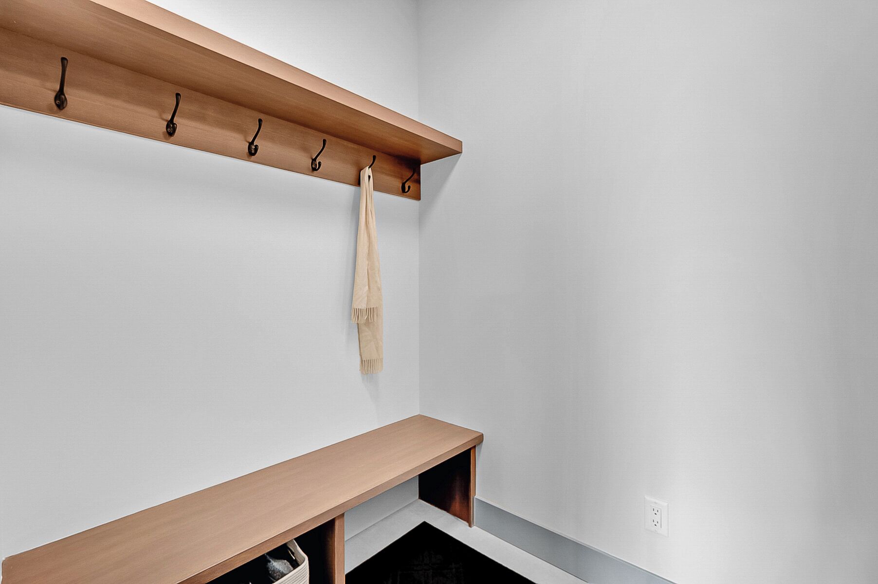 A corner of a room with a wooden shelf, a coat rack, and a bench.