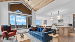 A spacious living area with a blue sofa, red armchair, and a wooden coffee table. - Western Star Chalet Ski In Out w Mtn View (Beaverdell)