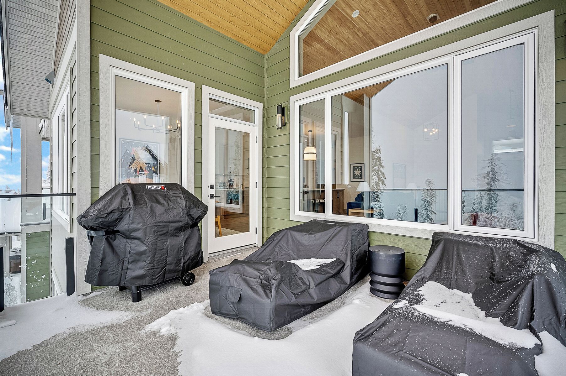 A covered porch with a sliding glass door, a covered seating area, and a covered grill.