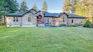 A two-story stone house with a front porch, a stone fireplace, and a well-maintained lawn. - Private Lake, Amazing View, Hot Tub, Forest Trail (Long Beach)