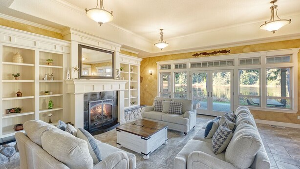 A spacious living room with a fireplace, comfortable seating, and large windows offering a view of the outdoors. - Private Lake, Amazing View, Hot Tub, Forest Trail (Long Beach)