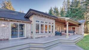 A house with a deck, large windows, and a covered outdoor seating area. - Private Lake, Amazing View, Hot Tub, Forest Trail (Long Beach)