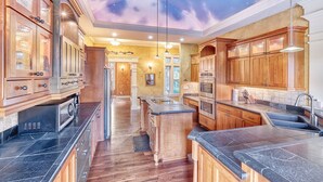 A spacious kitchen with wooden cabinets, a central island, and a ceiling with a starry night design. - Private Lake, Amazing View, Hot Tub, Forest Trail (Long Beach)