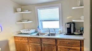 A kitchen with wooden cabinets, a stainless steel sink, and a coffee maker.