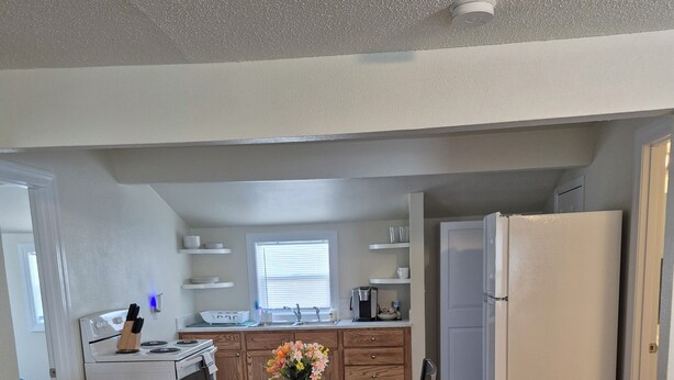 A modern kitchen with white cabinets, a stainless steel sink, and a built-in oven.
