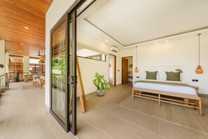 Ein modernes Schlafzimmer mit einem großen Bett, einem Essbereich mit Tisch und Stühlen und Blick auf eine Holzbalkendecke.