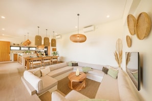 A modern living room with a sectional sofa, a dining area, and a kitchen in the background.