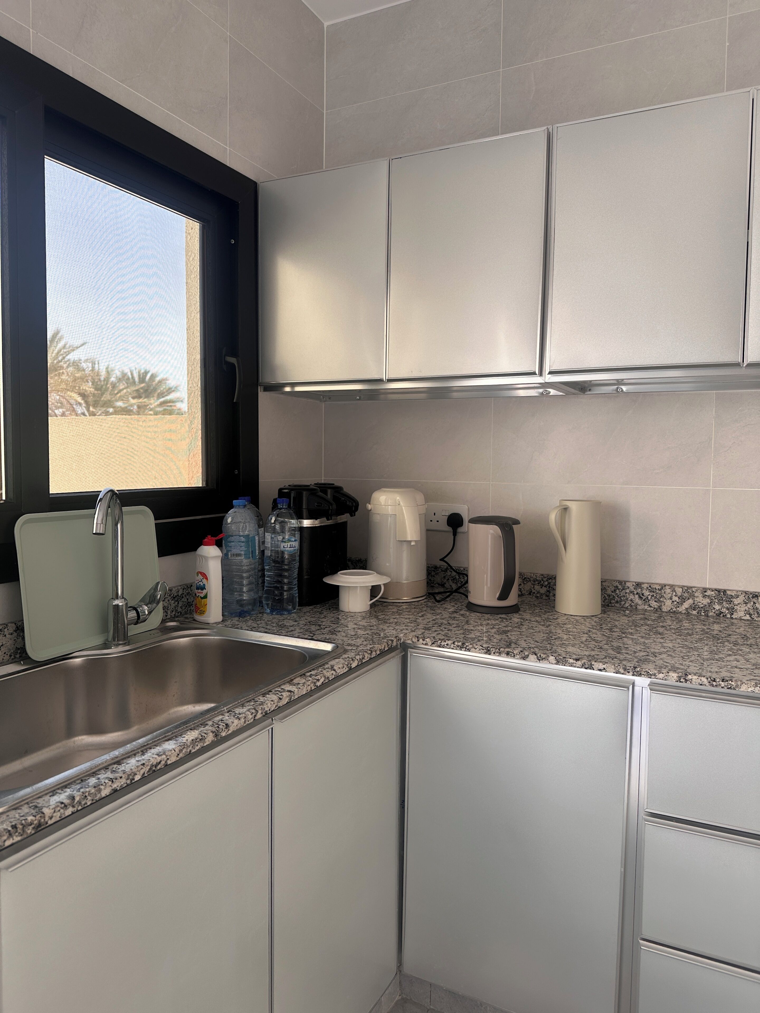Een moderne keuken met een granieten aanrecht, een roestvrijstalen spoelbak en witte kastjes.