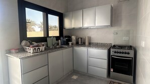 Una cucina compatta con piano cottura a gas, mobili a incasso e una finestra vista palme.
