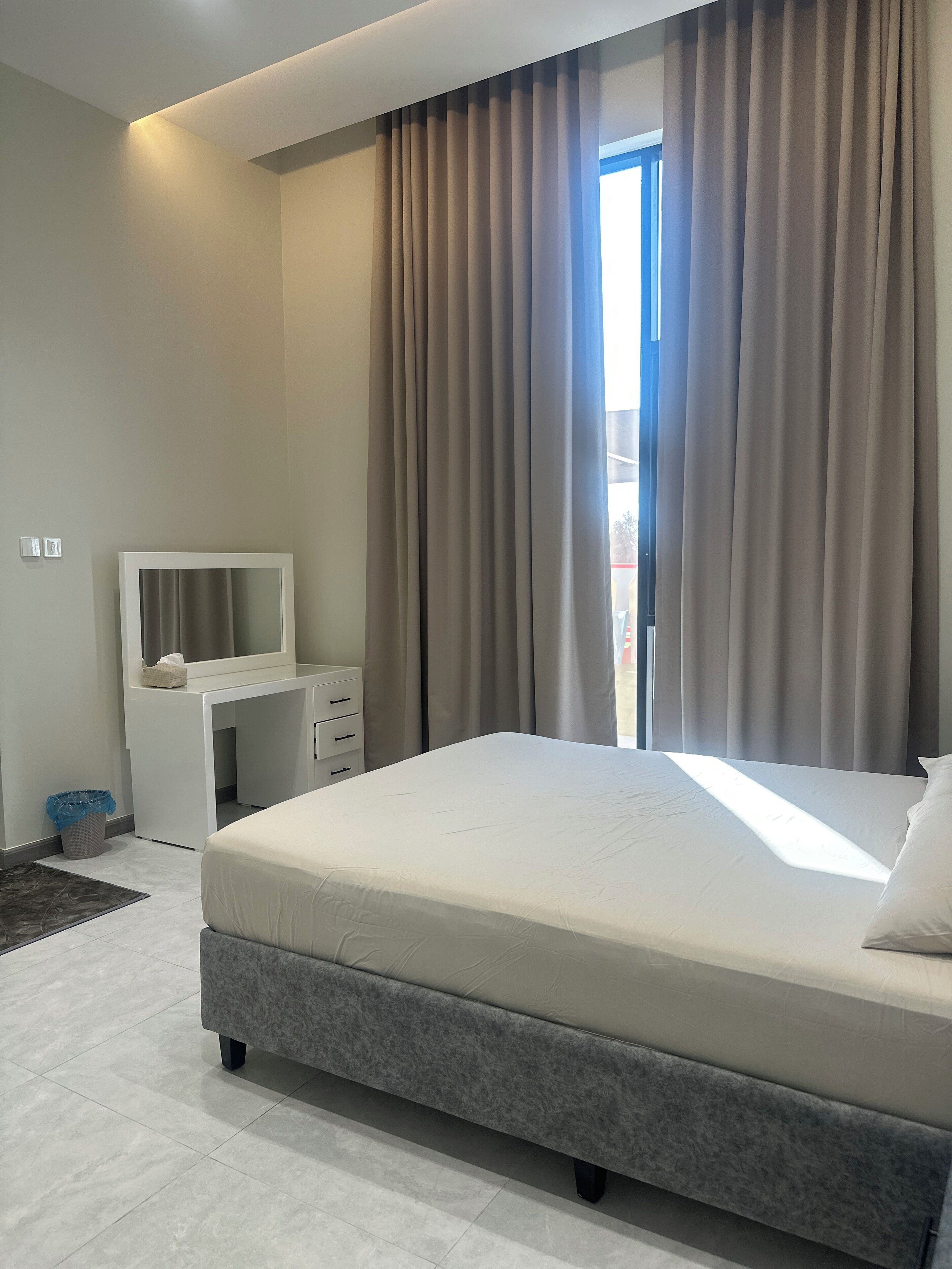 Een moderne hotelkamer met een groot bed, een nachtkastje met spiegel en een bureau.