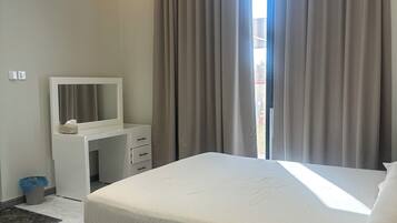 Een moderne hotelkamer met een groot bed, een nachtkastje met spiegel en een bureau.
