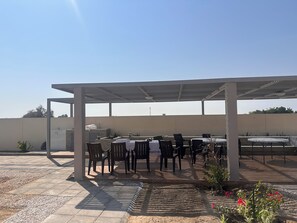 An outdoor patio area with tables and chairs, a covered seating area, and a water feature.