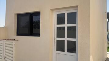 Een modern gebouw met een witte gevel, een groot raam en een deur met glaspanelen.