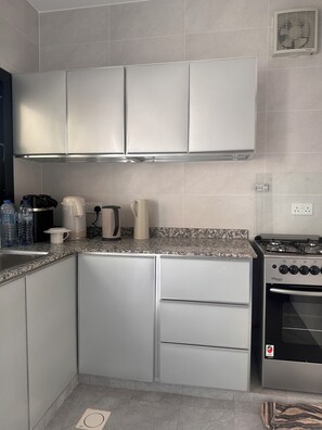 A modern kitchen with stainless steel appliances, a granite countertop, and white cabinetry.