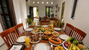 A dining table set with various dishes, fruits, and a glass of orange juice. - Hilltop Retreat Matale (Walewela)