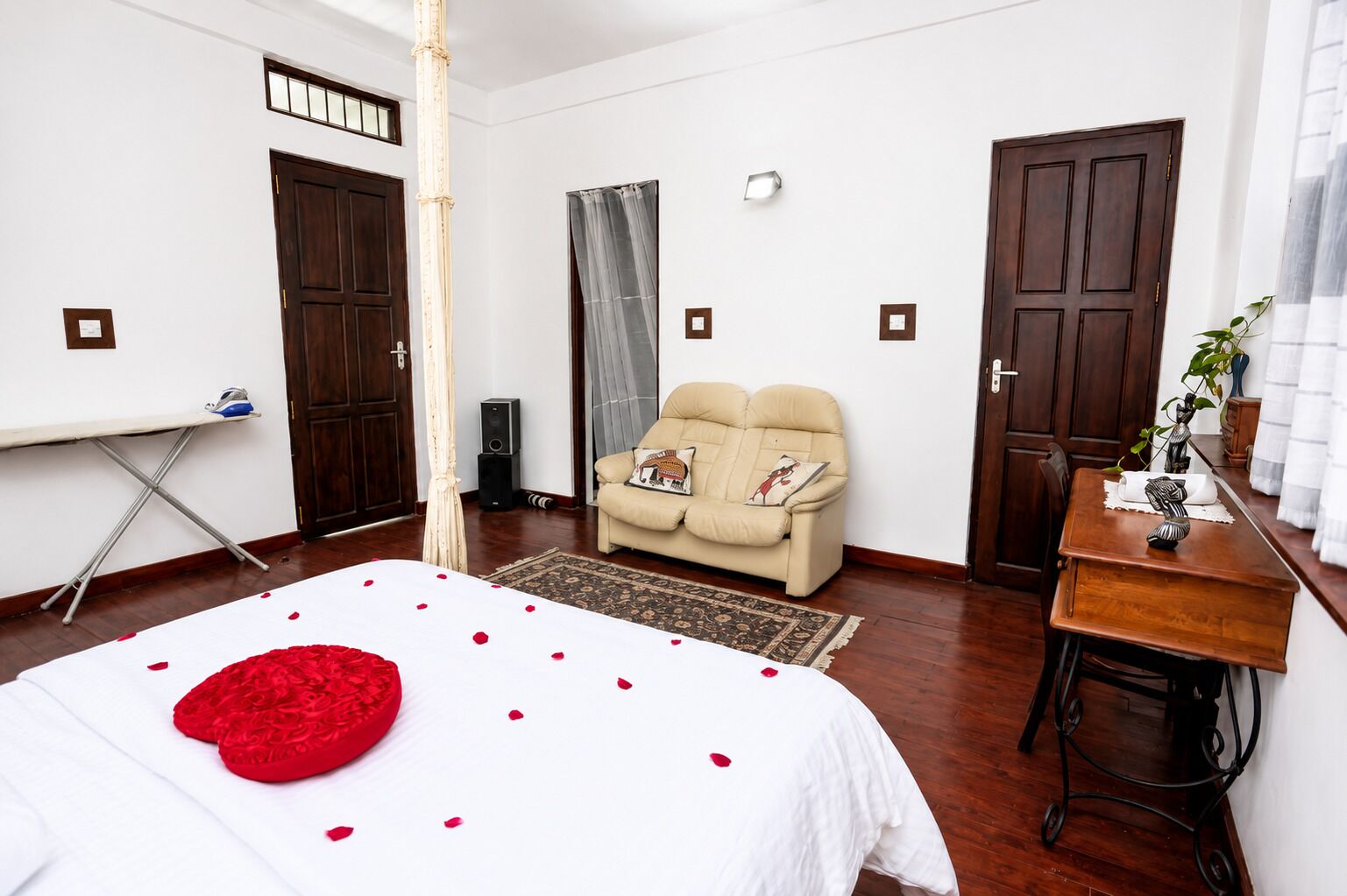 A bedroom with a bed, a sofa, a dining table, and two doors.
