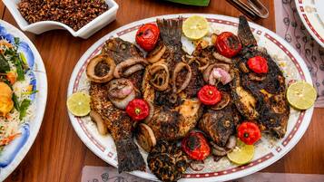 A plate of grilled fish with vegetables and a side of rice.