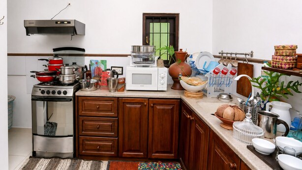 Una cocina con estufa, microondas, armarios y diversos utensilios.