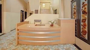 Ein Empfangsschalter mit gefliestem Boden, einer Treppe und gerahmten floralen Bildern an den Wänden.