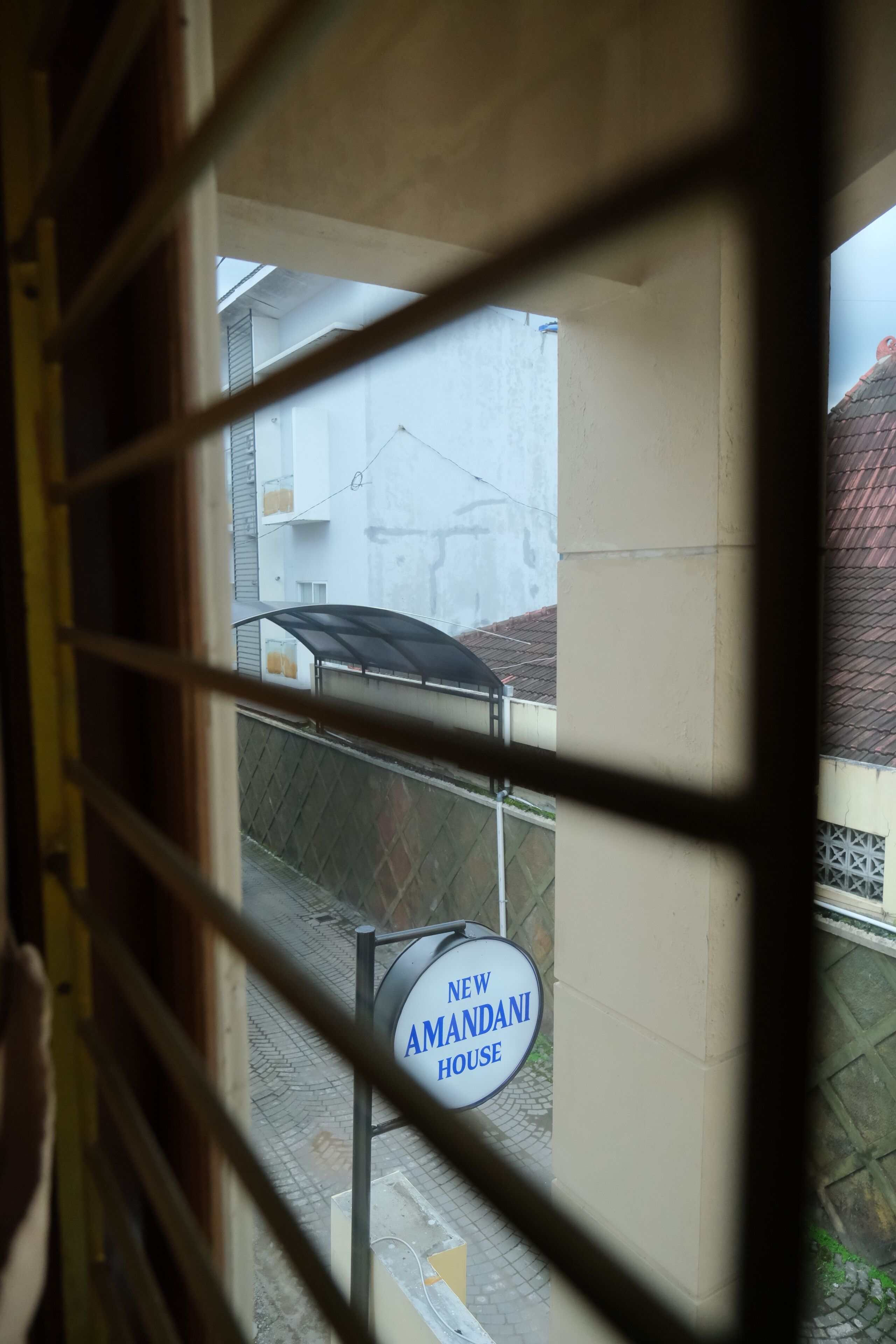 A view through a window with a sign reading "New Amanda House."