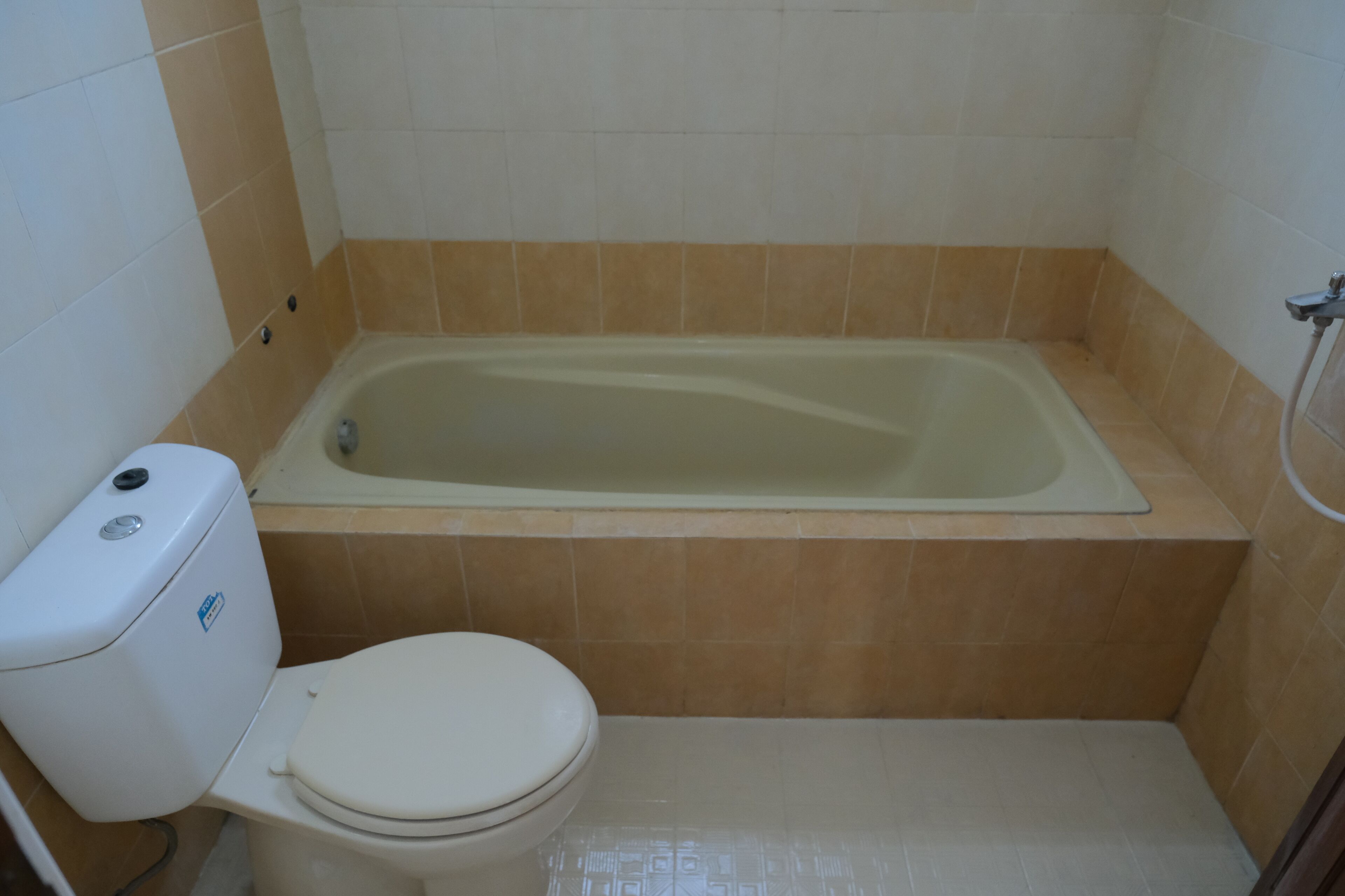 A bathroom with a bathtub, toilet, and tiled walls.