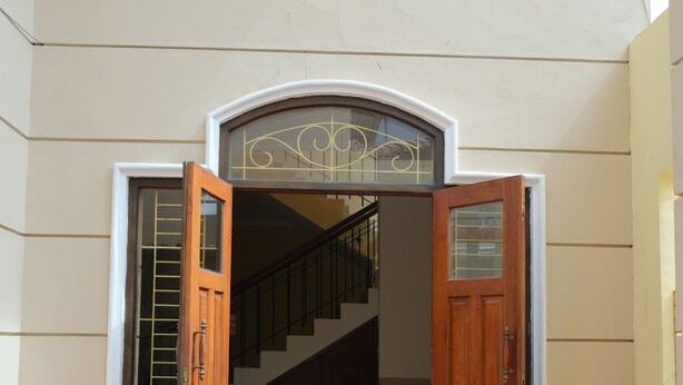Una escalera que conduce a un piso superior, con una puerta de madera y paneles de vidrio a cada lado.