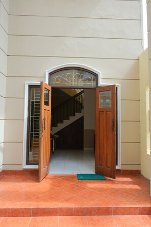 A staircase leading to an upper floor, with a wooden door and glass panels on either side. - New Amandani House (Depok)