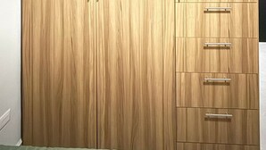 Un armario grande con varios cajones y puertas, un ventilador de techo y una cama con colcha verde.