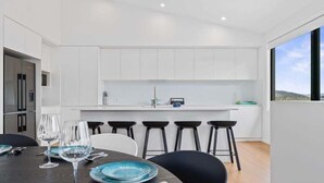 Una cocina moderna con armarios blancos, una isla central y un comedor con sillas negras y una mesa dispuesta para cuatro.