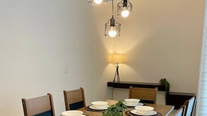 Ruokailutilassa on puinen pöytä, johon on katettu neljälle, ja sen ympärillä on tummin tyynyin varustettuja tuoleja.
